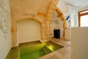 a room with a stone wall and green flooring at Il Fico Luxury Suite & SPA in Polignano a Mare