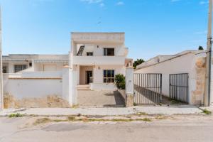 a white house with a gate in front of it at Le Ville di Sofia by BarbarHouse in Sant'Isidoro