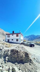 a white building on a rocky hill with cars parked in front at LSN Homestay By Soma Stays in Kaza