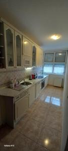a kitchen with white cabinets and a tile floor at Favorite apartment in Hévíz