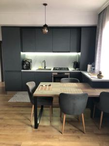 a kitchen with black cabinets and a wooden table and chairs at Apartament Icas in Dej