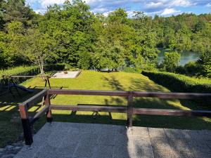 a wooden bench sitting on a walkway next to a park at Pixie House - Mrežnica, private pier, hot tub in Gornji Zvečaj