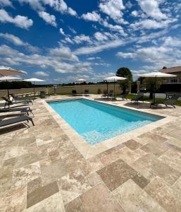 a pool with chairs and umbrellas on a patio at Maltus - Le Repaire de Maltus "Gîtes & Spa" in Lussac +11 photos