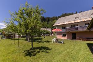 a house with a yard with a tree and an umbrella at Apartmaji Trstenjak in Rateče