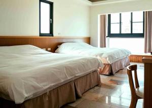 two beds in a bedroom with a window at Grand Uncle in Ta-p'ai-chu +2 photos