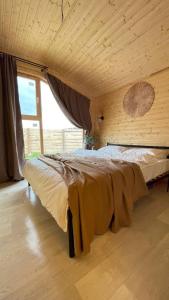 a large bed in a room with a large window at Экохаус Бурабай 1 in Borovoye