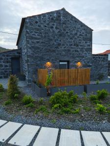 a stone house with a wooden fence in front of it at Cá Por Casa Pico-Faia in Prainha de Baixo