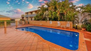 a swimming pool in front of a house at Emerald Gardens Motel & Apartments in Emerald