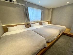 two twin beds in a room with a window at TABISAI HOTEL Terrace 博多 in Fukuoka