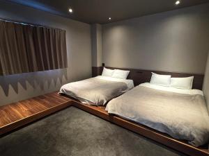 two twin beds in a room with a window at TABISAI HOTEL Terrace 博多 in Fukuoka
