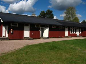 um celeiro vermelho e branco com um telhado preto em Klarälvens Camping em Stöllet
