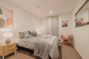 Un dormitorio con una cama y una silla rosa. en Convenient City Pad - 2BR Laundry Sleeps 5, en Christchurch
