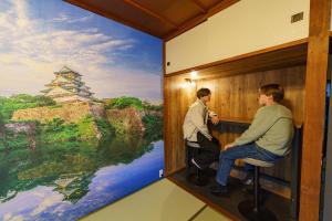 two people sitting in a room with a painting on the wall at SAMURAI Base in Hakone