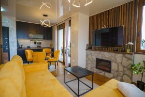 a living room with a yellow couch and a fireplace at Apart kompleks Binis in Zlatibor +50 photos