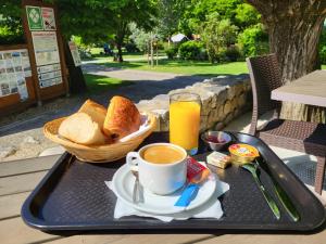 a tray with toast and a cup of coffee and a basket of bread at Camping La Charderie in Pont-de-Labeaume