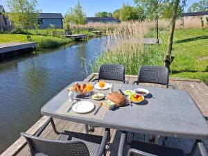 un tavolo da picnic con cibo su una barca su un fiume di De IJssel Eilanden Chalet Casa Kampen mit Zaun Nr 548 a Kampen