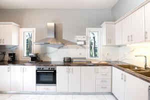 una cucina con mobili bianchi e un lavandino di Villa Kerkyra a Gouviá Altre 34 foto