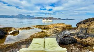 KástronMilos Boathouse-Between2seas Boutique的水中的小船，岩石上的床