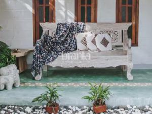 a wooden bench with pillows sitting on a patio at Branta Home Homestay Yogyakarta in Timuran +3 photos