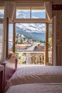 een slaapkamer met een groot raam met uitzicht op de bergen bij Historic Hotel Falken in Wengen