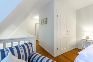 a white room with a bed and a door at Landhaus Butt 05 in Ahrenshoop