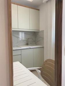 a kitchen with white cabinets and a sink and a chair at Relax Apartments SB in Himare