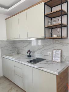 a kitchen with white cabinets and marble counter tops at Relax Apartments SB in Himare +17 photos