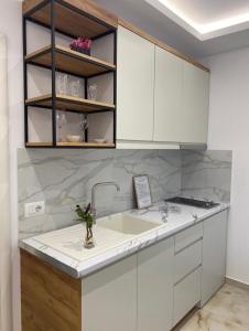 a kitchen with white cabinets and a sink at Relax Apartments SB in Himare