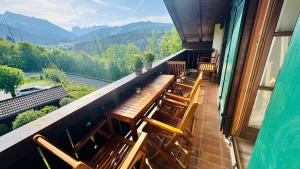 Un balcón con bancos de madera y vista a las montañas. en Ferienwohnung BergSucht, en Schönau am Königssee