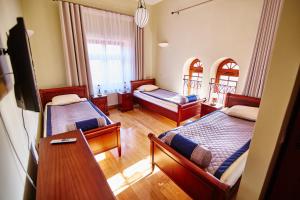 a room with two beds and a desk and a television at Centrum Obsługi Turysty Kordegarda in Raczki +18 photos
