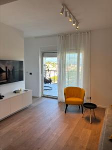 a living room with an orange chair and a television at Apartman Zalar in Lopar