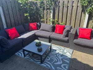 a patio with couches and a table with red pillows at Queens Beachhouse in Zandvoort