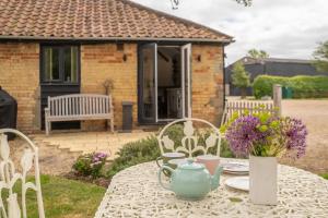 une table avec une théière et des fleurs dessus dans l'établissement East Green Farm Cottages - The Old Stables, à Saxmundham