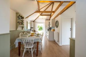 une cuisine et une salle à manger avec une table et des chaises dans l'établissement East Green Farm Cottages - The Old Stables, à Saxmundham