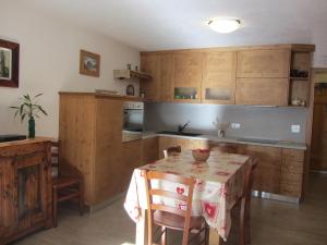 a kitchen with wooden cabinets and a table with a table cloth at Les Racines in Rhêmes-Notre-Dame
