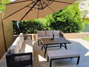 a patio with a table and chairs and an umbrella at Apartman Dea in Mali Lošinj