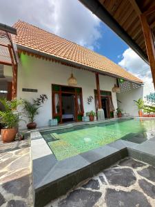 a villa with a swimming pool in front of a house at Omah Jago Sentana Yogyakarta in Timuran