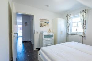 a white bedroom with a bed and a window at Arielle in Norddeich