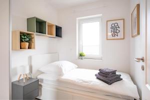 a white bedroom with a bed and a window at Wackenhuus 4 Albersdorf in Albersdorf