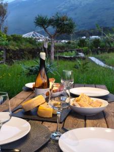 a wooden table with a bottle of wine and wine glasses at Cá Por Casa Pico-Criptoméria in Prainha de Baixo