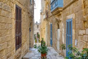 an alley in an old town with blue shutters at Studio apartment 2 with private kitchenette at the New Casa Vittoria by SF Homes in Cospicua