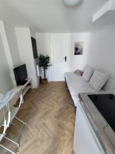 a white living room with a bed and a television at appartement cosy entier et parking privé sur place a 5min de lille et 10 min du Stade Pierre Mauroy in Mons-en-Baroeul