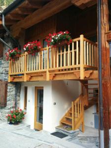 a house with a wooden balcony with flowers on it at Les Racines in Rhêmes-Notre-Dame