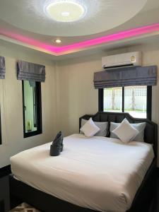 a bedroom with a large white bed with a pink lighting at VS Resortวีเอส รีสอร์ท ท่าศาลา in Ban Thang Khun