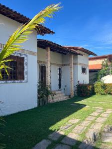 a white house with a palm tree in the yard at Casa de Praia - Praia Bela in Aquiraz
