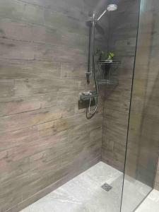 a bathroom with a shower with a wooden wall at Studio with kitchen nestled lovely wooded cul du sac in New Malden +23 photos