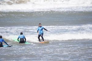 a man riding a wave on a surfboard in the ocean at Santacruz Surf Camp Morocco in Tamraght Ouzdar