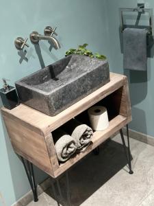 a stone sink on a wooden stand in a bathroom at Studio with kitchen nestled lovely wooded cul du sac in New Malden