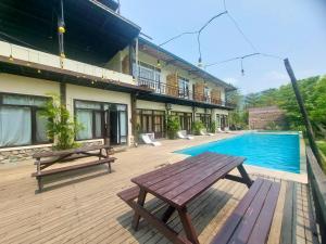 una terraza de madera con una mesa de picnic junto a una piscina en Landmark Farmhouse, en Bharatpur