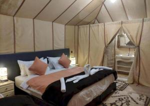 una camera da letto con un letto in una tenda di Erg Elysia Camp a Merzouga